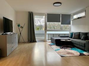 uma sala de estar com um sofá e uma televisão em LaMiaCasa Design Apartment near Ludwigsburg 2,5 rooms 75 sqm em Schwieberdingen