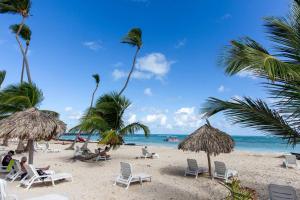 a beach with chairs and palm trees and the ocean at The Ultimate Escape Unpack Relax Enjoy in Punta Cana