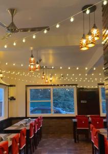 uma sala de jantar com mesas, cadeiras e luzes em Kafal Gates em Lansdowne