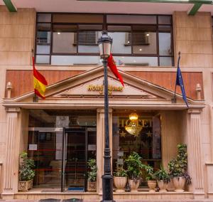 una luz de la calle con banderas delante de un edificio en Hôtel Atenas, en Tetuán