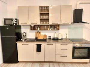 cocina con armarios blancos y nevera negra en Summer Haven- self check-in, parking, netflix, terrace, near mall en Oradea