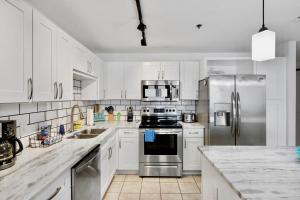 a kitchen with white cabinets and stainless steel appliances at Luxurious 4 Bedroom Condo! Gulf Views! Sleeps 10 & Easy Beach Access! by Dolce Vita Getaways PCB in Panama City Beach