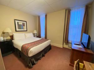 a hotel room with a bed and a desk and a television at Hotel Bedford in Goderich