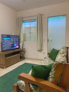 ein Wohnzimmer mit einem Sofa und einem Flachbild-TV in der Unterkunft Casa aconchegante e charmosa à 6 min da Praia - Ar condicionado - WIFI 600MB - Netflix - Globoplay - Cozinha Completa in Rio das Ostras