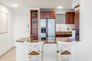 een keuken met twee witte barkrukken en een koelkast bij Maho Beach 1-BR Ocean Suite in Maho Reef