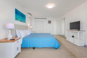 ein Schlafzimmer mit einem blauen Bett und einem TV in der Unterkunft Sunset Beach Condo - Luxury 1BR Suite next to The Morgan Resort in Maho Reef