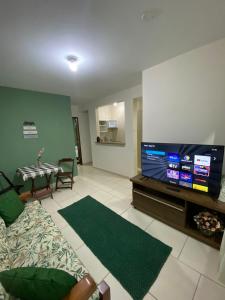 ein Wohnzimmer mit einem TV und einem Tisch in der Unterkunft Casa aconchegante e charmosa à 6 min da Praia - Ar condicionado - WIFI 600MB - Netflix - Globoplay - Cozinha Completa in Rio das Ostras