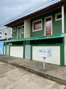 a green and white building with a sign in front of it at Casa aconchegante e charmosa à 6 min da Praia - Ar condicionado - WIFI 600MB - Netflix - Globoplay - Cozinha Completa in Rio das Ostras