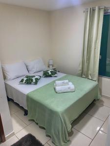 2 Betten in einem Zimmer mit grüner Bettwäsche und Handtüchern in der Unterkunft Casa aconchegante e charmosa à 6 min da Praia - Ar condicionado - WIFI 600MB - Netflix - Globoplay - Cozinha Completa in Rio das Ostras