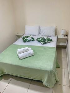 a bed with green sheets and towels on it at Casa aconchegante e charmosa à 6 min da Praia - Ar condicionado - WIFI 600MB - Netflix - Globoplay - Cozinha Completa in Rio das Ostras