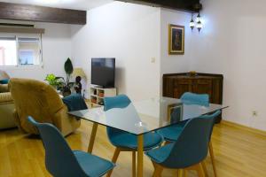 a living room with a glass table and blue chairs at Al pie del Camarín con parking gratis in Jaén