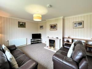 a living room with a couch and a fireplace at Westerdale in Fort Augustus