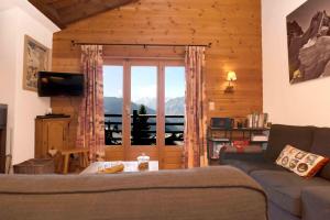 een woonkamer met een bank en een groot raam bij Magnifique Ski in/out, cosy and calm, 4 bedrooms in Verbier