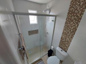 a bathroom with a shower and a white toilet at Apartamento Descubra Palhoça - Pinheira in Palhoça +21 photos