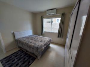 a small bedroom with a bed and a window at Apartamento Descubra Palhoça - Pinheira in Palhoça