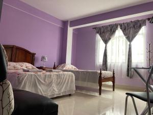 a purple bedroom with two beds and a window at El Grano De Oro Hotel in Tupiza