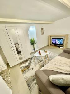 ein Wohnzimmer mit einem Sofa und einem TV in der Unterkunft Entre Paris, Versailles et La Défense in Chaville