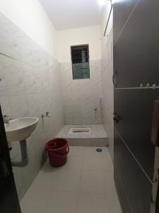 a white bathroom with a sink and a toilet at Shri Vasant Lodge in Hubli