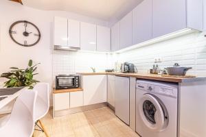 una cocina con gabinetes blancos y una lavadora y secadora en New Loft in the Heart of City Center, en Heraclión 12 fotos más