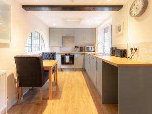 a kitchen with a table and a clock on the wall at The Annexe in Wisley