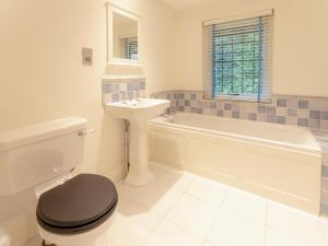a bathroom with a tub and a toilet and a sink at The Annexe in Wisley