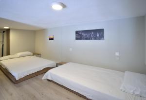 ネア・ポティダイアにあるSuite Loft Apartment Konstantinidisの白い壁とウッドフロアの客室で、ベッド2台が備わります。
