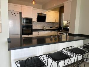 a kitchen with black counter chairs and white cabinets at Villa Oğuz in Milas