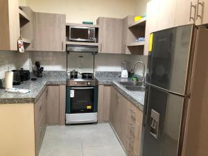 a kitchen with a refrigerator and a stove and a sink at Garzota Garden PB in Guayaquil