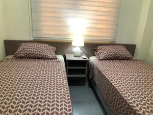 1 dormitorio con 2 camas y mesa con lámpara en Garzota Garden PB, en Guayaquil