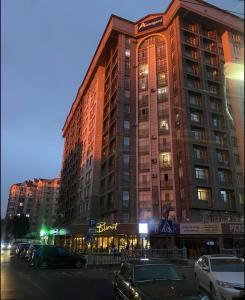 ein großes Gebäude mit davor geparkt in der Unterkunft Apartment elit Bishkek in Bischkek