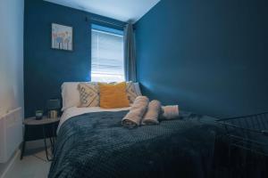 ein blaues Schlafzimmer mit einem Bett mit Kissen und einem Fenster in der Unterkunft Stayright Stylish Cardiff Bay 2 Bed Apartment- Private Parking & 10 mins to Bay & City in Cardiff