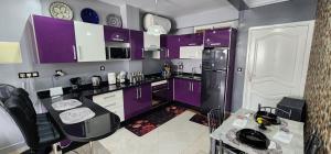 een keuken met paarse kasten en een zwarte koelkast bij Luxury Beach Apartment with Balcony, free Wi-Fi & AC in Tanger
