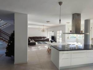 a kitchen and living room with white cabinets and a table at Casa Anton - Villa ideal familias y grupos grandes, piscina privada in Alcanar