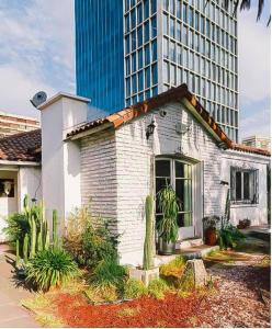 een klein wit huis voor een hoog gebouw bij Pieza independiente en casa compartida en Vitacura cn bici y piscina in Santiago