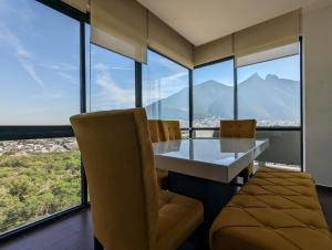 ein Esszimmer mit einem Tisch, Stühlen und Fenstern in der Unterkunft Moderno Ubicacion Vistas Seguridad y Estilo in Monterrey
