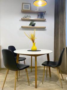 a dining room table with chairs and a yellow vase on it at Stylish apartment in the historic center in Chernihiv