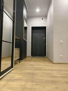 a hallway with a black door and a wooden floor at Stylish apartment in the historic center in Chernihiv