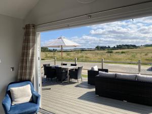 a patio with a table and chairs and an umbrella at Prospect Lodge at The Bay Filey, sleeps up to 6, and 2 dogs stay for free! in Filey