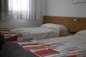 a room with three beds in a room at Pension Txiki in Isaba