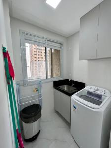 una pequeña cocina con fregadero y lavadora en Apartamento próximo à praia, en Itapema