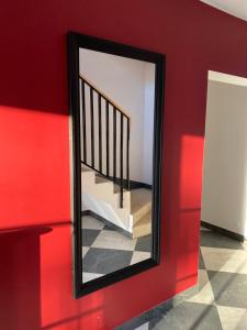 Ein Spiegel hängt an einer roten Wand neben einer Treppe. in der Unterkunft Lux Studio HOTEL in Keila
