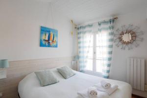 Un dormitorio con una cama blanca con toallas. en Sur l'îlot de St Martin au centre du port vue exceptionnelle !, en Saint-Martin-de-Ré