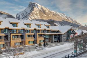 a hotel with a snow covered mountain in the background at Peaks Hotel and Suites in Banff