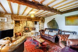 a living room with leather furniture and a stone fireplace at Pant Yr Iwrch in Conwy
