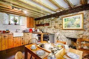 a kitchen with a table and a stone wall at Pant Yr Iwrch in Conwy