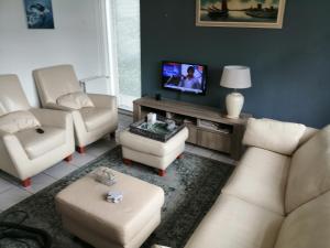een woonkamer met witte meubels en een flatscreen-tv bij Mooie twee-onder-een-kapwoning te Vlagtwedde in Vlagtwedde