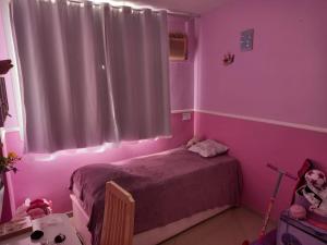Dormitorio rosa con cama y mesa en Barra Beach, en Río de Janeiro