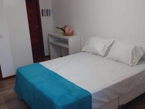 a white bed with a blue blanket on top of it at Casa em Barra Grande com piscina in Marau