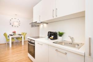 a white kitchen with a sink and a table at Premium City Apartment with balcony! Free Garage Parking included! in Vienna