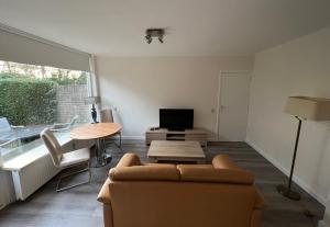 ein Wohnzimmer mit einem Sofa, einem Tisch und einem TV in der Unterkunft Bosvakantie Veluwe - Huisje 54, Hoefbos, Otterlo in Otterlo